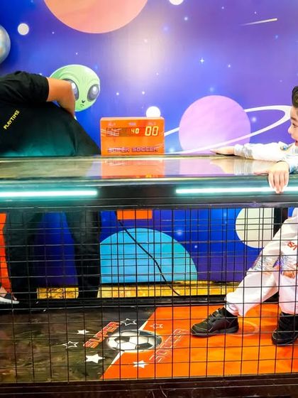 Kids engrossed in a game of mini table football, a great interactive game that encourages friendly competition.