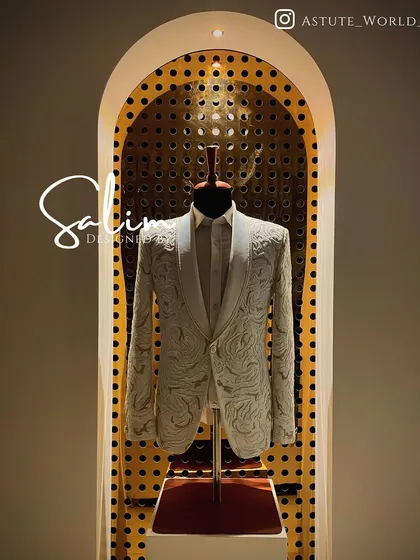 A white tuxedo jacket with intricate all-over white embroidery, displayed in my studio. This is a stunning option for a groom who wants a luxurious, textured look.