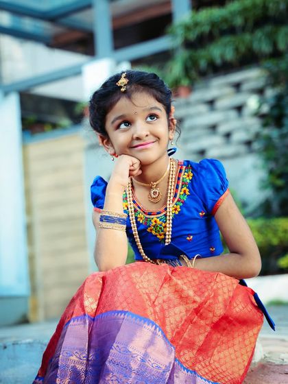 A thoughtful portrait of a young girl in a traditional pattu pavadai. Her dreamy expression and beautiful attire make for a timeless and elegant photograph.