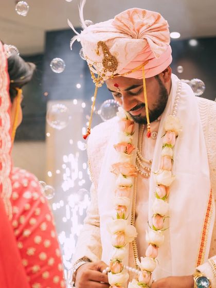 A candid shot of the groom during the varmala ceremony, with soap bubbles adding a dreamy and whimsical touch.