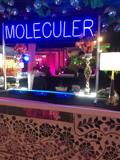 A stylish molecular bar with a mosaic tile front and a bright blue neon sign. This setup is perfect for adding a modern and colorful touch to any party.
