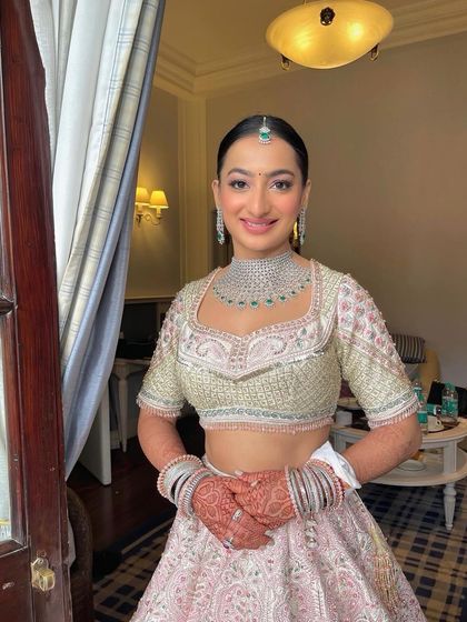 A happy bride ready for her daytime wedding. I created a sleek, clean bun and adorned it with a crown of pink flowers to match her lehenga.