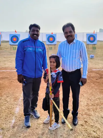 A young archer poses with her coach and an official at the state competition, a proud moment for our academy.