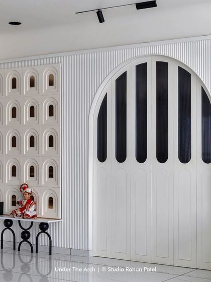 A large, arched folding door with fluted glass panels separates spaces while allowing light to pass through, echoing the arch motifs seen throughout the home.