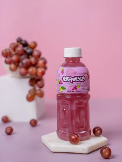 A grape-flavored drink styled with fresh grapes on a marble coaster. The use of levels and fresh ingredients adds a touch of sophistication to this beverage shot.