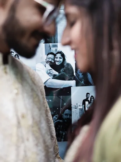 A creative shot where the couple's love story is literally in the background. This photo from their engagement shoot cleverly incorporates their memories into a new, romantic moment.