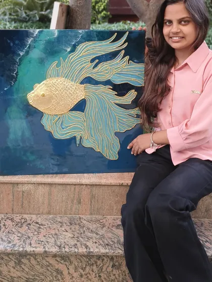 A student proudly displays the beautiful golden fish texture art she created in our professional class. This piece combines cone work, gold foil, and resin for a stunning 3D effect.