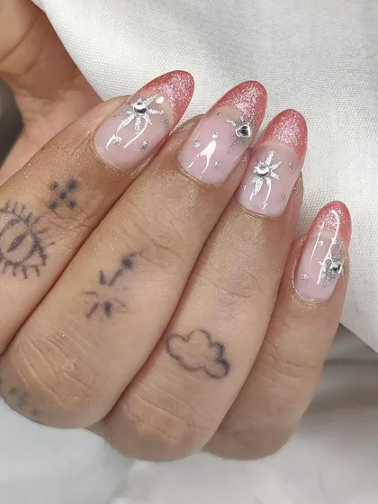 A close-up of the pink glitter celestial nails, showing the detail of the starburst charms.
