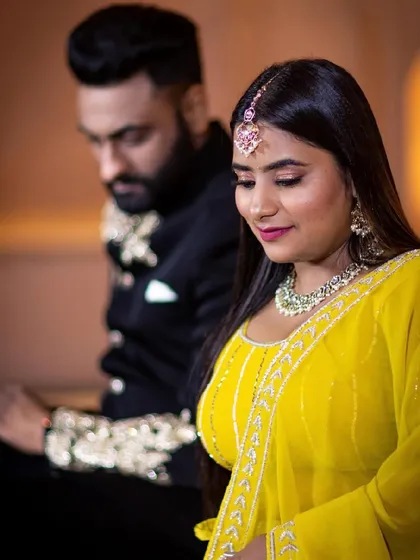 A close-up of the bride-to-be in a vibrant yellow outfit. The makeup is fresh and dewy with a pop of color on the lips to match the festive mood.