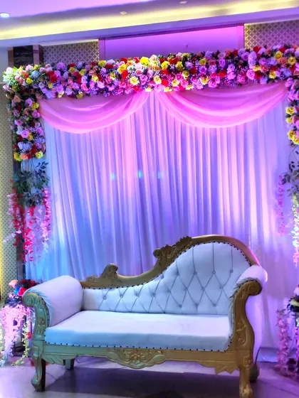 A slightly different perspective of the floral stage setup, emphasizing the hanging wisteria flowers and the rich colors of the floral arrangement.