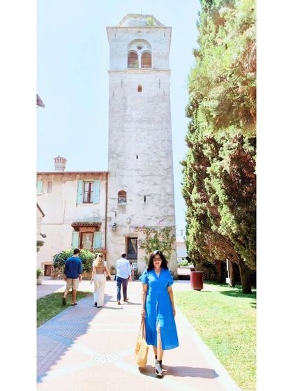 A full shot of the blue linen dress against a beautiful tower in Sirmione. This dress was a comfortable and photogenic choice for a day of sightseeing.