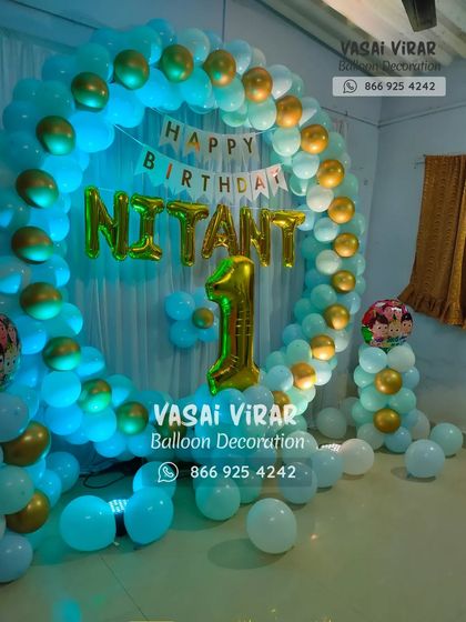 A simple and elegant ring backdrop for a first birthday. The combination of light blue and gold balloons creates a classic look, personalized with the birthday boy's name and a large number '1' foil balloon.