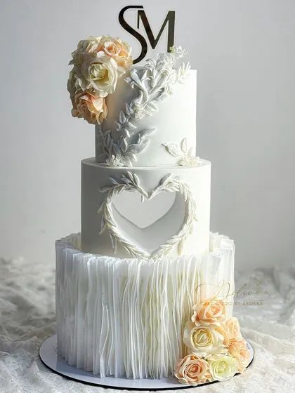 Elegance is in the details. This three-tier wedding cake features delicate wafer paper ruffles and intricate bas-relief details, techniques we can explore to elevate your cake designs.