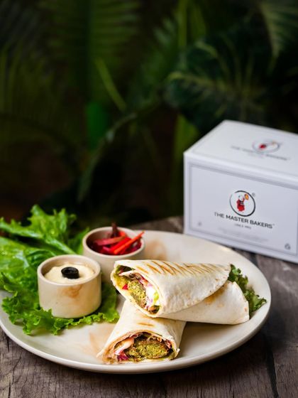 Our finished Falafel Wrap, cut in half to reveal the delicious fillings inside. It's served with hummus and pickled vegetables on the side.