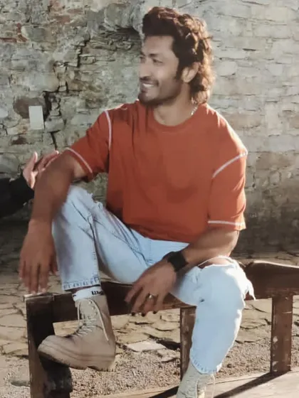 A relaxed moment with Vidyut Jammwal between takes. His costume here is a simple orange t-shirt, distressed jeans, and combat boots, creating a rugged look for his character.