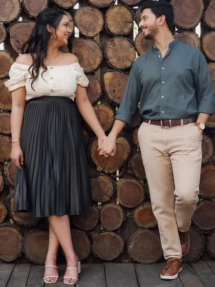For this part of the pre-wedding shoot, we used a rustic woodpile as a textured backdrop. I styled the couple in smart-casual outfits, with the bride in an off-shoulder top and pleated skirt, for a modern and relaxed couple portrait.