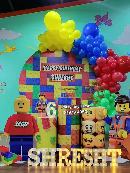A full view of the Lego-themed stage. The setup includes a custom backdrop, character props, and themed cake stands, all designed to look like giant Lego blocks.
