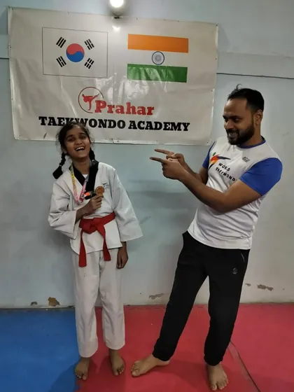 A fun, candid moment celebrating a red belt student's medal from the district tournament.
