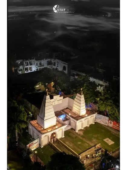 A pristine white temple-themed pandal captured from above during Durga Puja. The lighting makes it stand out against the dark night sky.