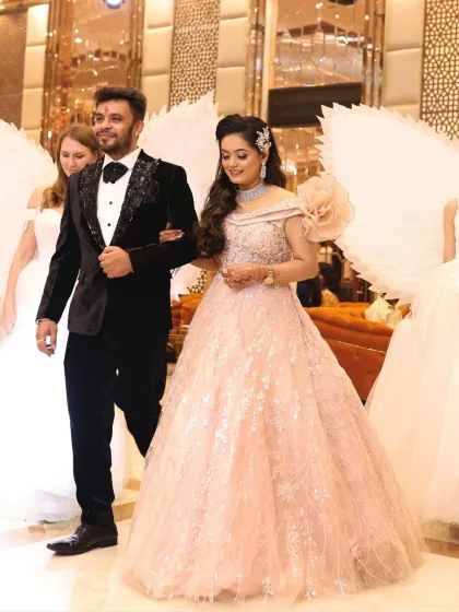 A full-length shot of the couple at their engagement. The bride's makeup is soft and luxurious, a perfect match for her blush pink gown.