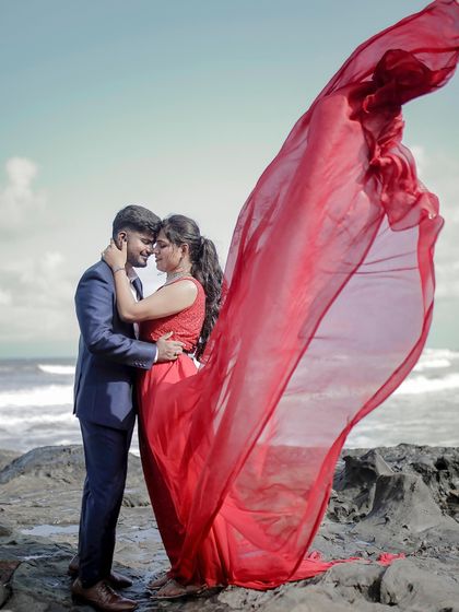 The wind-blown trail of this red gown creates a "flying" effect, adding drama and movement to this romantic pre-wedding embrace on the beach.