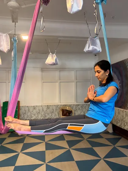 Aerial yoga isn't just about dynamic movement. It's also about finding moments of quiet and stillness, like in this seated pose where the hammock supports you in a gentle, floating meditation.