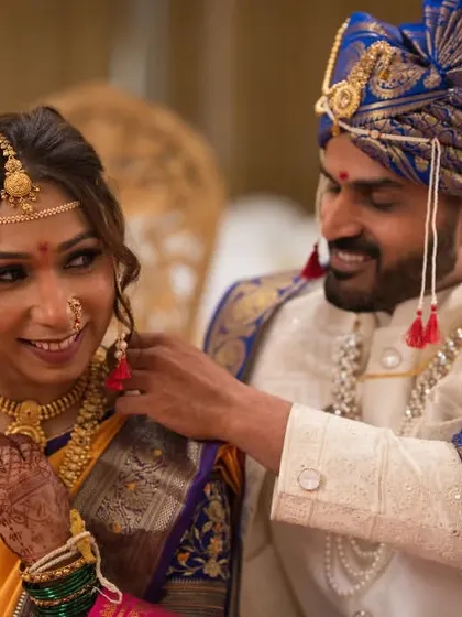 A candid, playful moment as the groom helps the bride with her jewelry. These are the unscripted memories we love to capture during a traditional Marathi wedding.