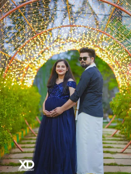 A magical evening shot of a couple in a tunnel of fairy lights, blending traditional and modern attire.