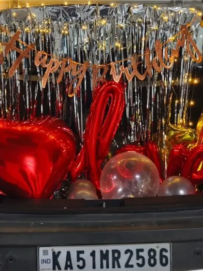A sparkling car boot decoration to surprise a wife on her birthday. We used red heart and 'LOVE' foil balloons with a shimmer curtain and fairy lights for a romantic reveal.