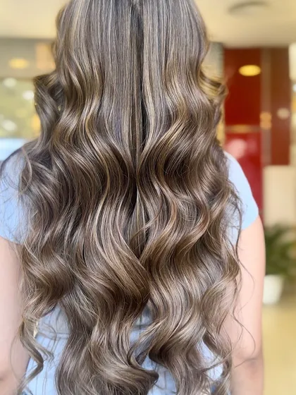 The full look of the caramel beige balayage. The long, flowing waves perfectly display the seamless blend of colors, from the darker roots to the lighter, caramel-toned ends.