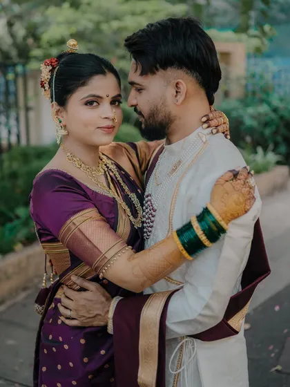 An intimate embrace that showcases the beautiful details of the bride's purple saree and traditional jewelry. This close-up captures the couple's connection and the richness of their wedding attire.
