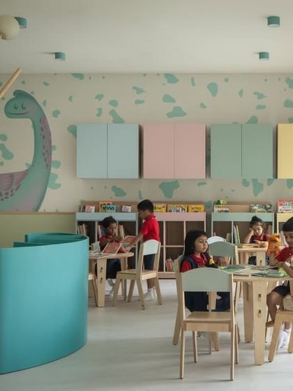 Children engaged in reading and playing in the library. The combination of tables for focused work and open areas for imaginative play makes this a truly versatile and well-loved space.