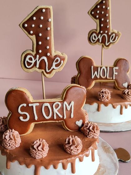 A detailed look at the matching first birthday cakes for Wolf and Storm. Each cake is personalized with their name on a cookie bone.