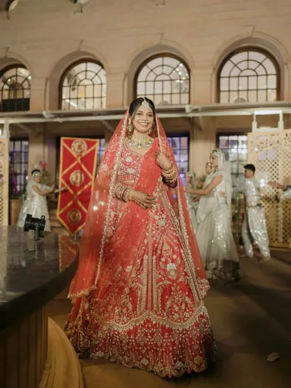 The bride's grand entrance! Her hair is styled in a traditional bun adorned with fresh flowers, completing her regal look as she walks in.