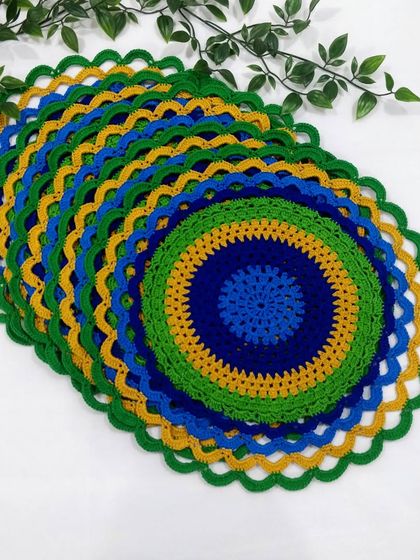 Another view of the stacked peacock placemats, highlighting the scalloped green border that finishes the design.