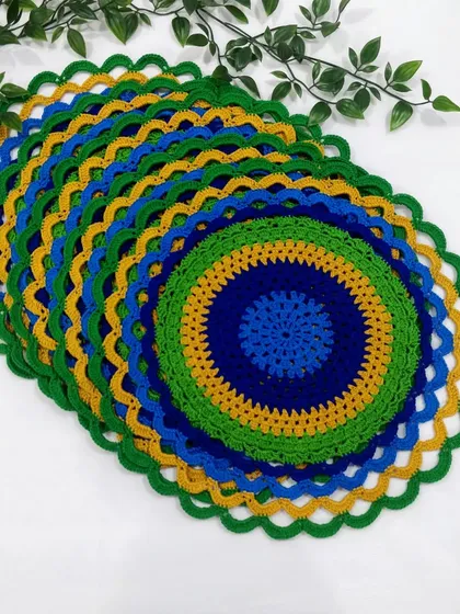 Another view of the stacked peacock placemats, highlighting the scalloped green border that finishes the design.