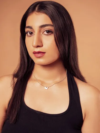 A direct, clean headshot. The focus is on the model's expression and the delicate butterfly necklace.