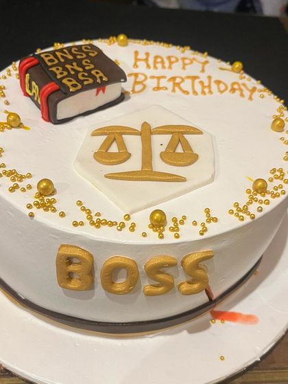 A close-up of the custom-made cake for my boss, featuring the scales of justice and a law book.