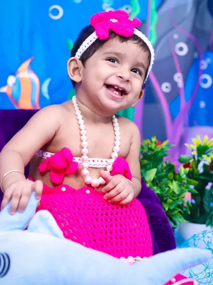 A joyful, laughing baby mermaid enjoying her under-the-sea photoshoot.