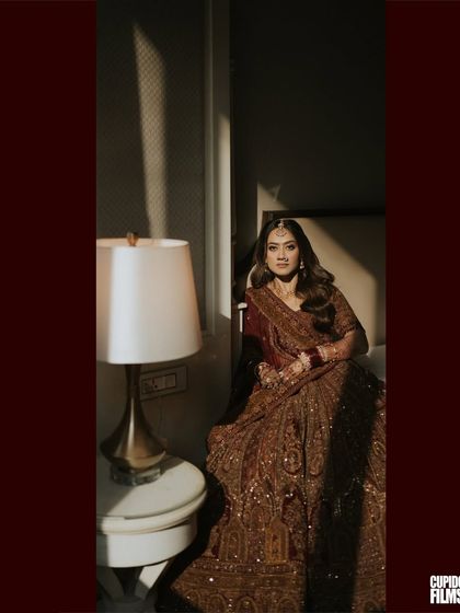 An artistic and moody portrait of the bride, Harita, in her stunningly detailed lehenga. The play of light and shadow adds a touch of drama and elegance to this Mumbai wedding shot.