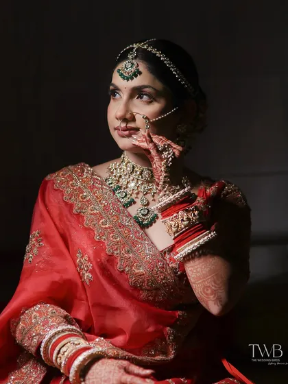 A moment of quiet reflection. This artistic bridal portrait uses dramatic side lighting to highlight the bride's features, her intricate jewelry, and the rich color of her saree.