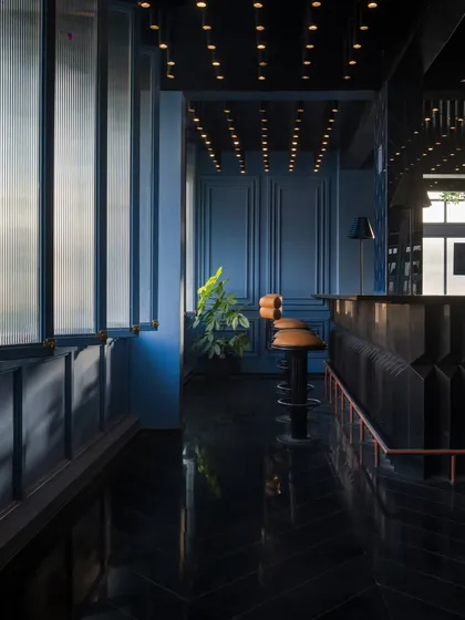 Light reflects off the polished black herringbone floor, adding depth and glamour to the bar's interior. The interplay of light and shadow is a key component of my design, used here to create a space that feels both intimate and dramatic.