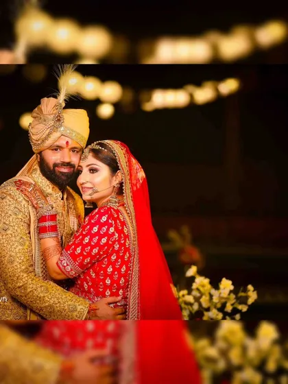 A happy portrait of the newlyweds. The bride is in a stunning red lehenga, and the groom in a golden sherwani, both smiling for the camera.