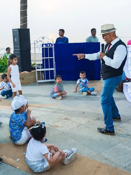 A party host engaging with young children at a beachside Sonic-themed party, leading them in fun games and activities.