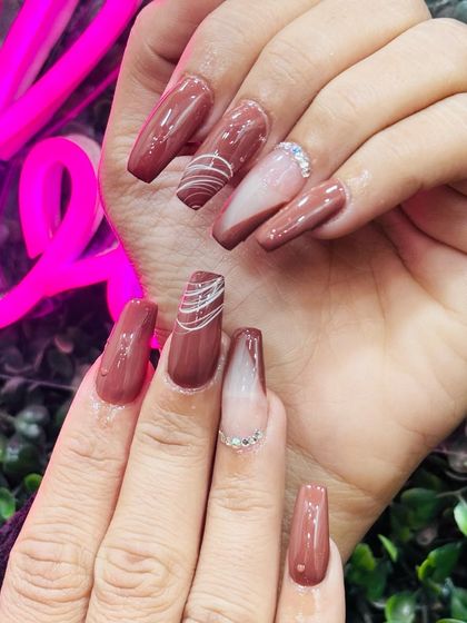 A chic and modern set of long coffin nails in a dusty rose color, with abstract white line art and rhinestone accents.