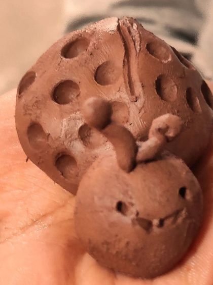 Tiny hands working hard to create a cute clay ladybug. Our kids' classes are great for developing fine motor skills and patience.