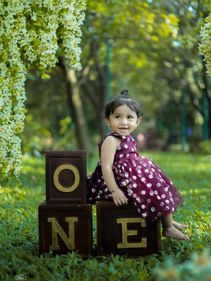An outdoor first birthday shoot celebrating one whole year of sunshine. This little girl sits proudly on "ONE" blocks in a beautiful park setting.