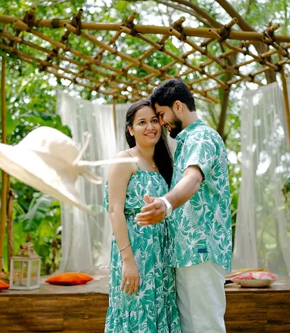 A candid moment of laughter during Harpreet and Simran's Bali-themed shoot. The matching tropical outfits and the breezy setup create a perfect vacation vibe.
