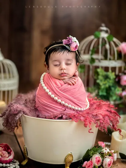 Elegance in miniature. This baby girl is styled with pearls and surrounded by soft pink tones and florals for a timeless, classic portrait.