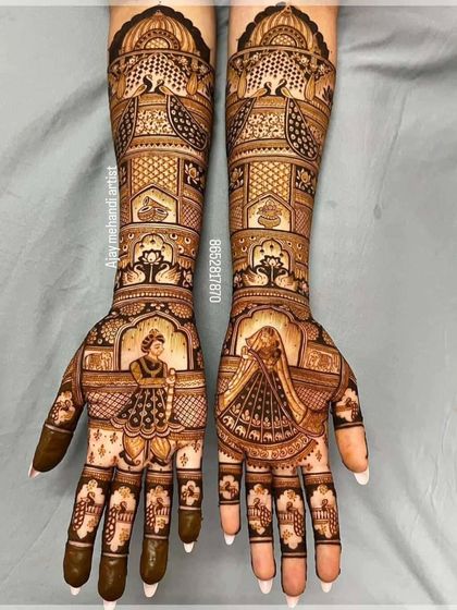 This design is a masterpiece of symmetry and detail. It features bride figurines in a doli, surrounded by peacocks, paisleys, and delicate floral work.